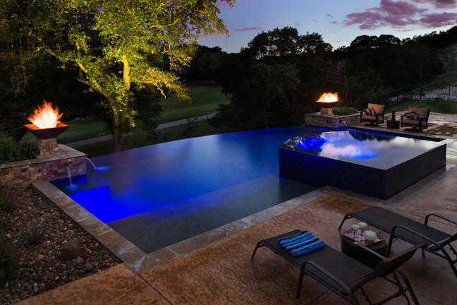 Imagen de piscina con fuente infinita actual de tamaño medio rectangular en patio trasero con losas de hormigón