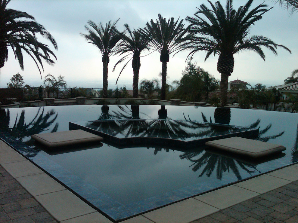 Photo of a medium sized back custom shaped natural swimming pool in Los Angeles with a water feature and natural stone paving.