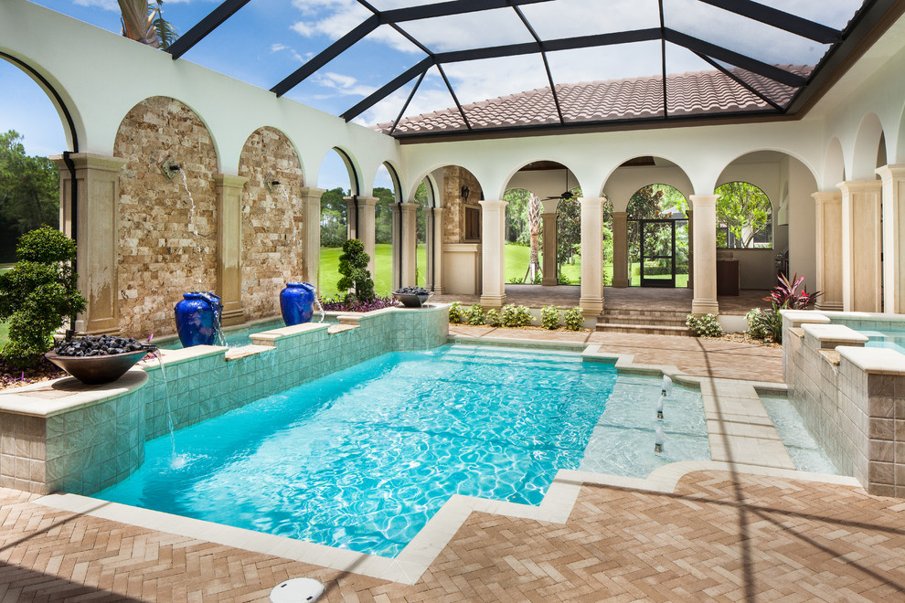 Пример оригинального дизайна: большой спортивный бассейн произвольной формы на заднем дворе в средиземноморском стиле с фонтаном и покрытием из каменной брусчатки
