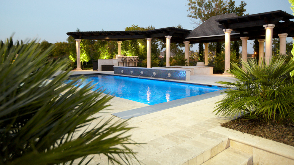 Photo of a large classic back rectangular swimming pool in Dallas with a water feature and natural stone paving.