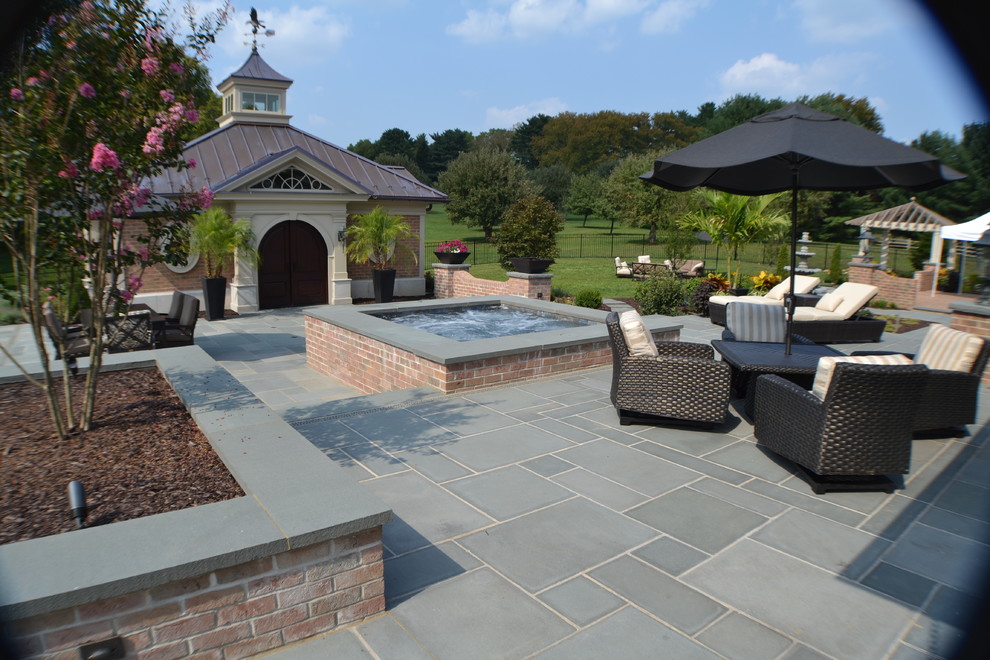 This is an example of a large classic back rectangular lengths swimming pool in Philadelphia with a water feature and natural stone paving.