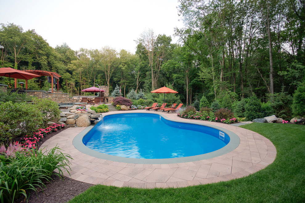 Large contemporary back kidney-shaped lengths hot tub in New York with concrete paving.