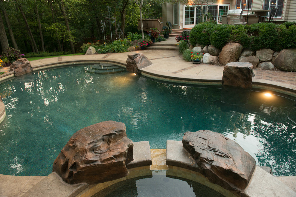 Photo of a small world-inspired back custom shaped hot tub in Cedar Rapids with stamped concrete.