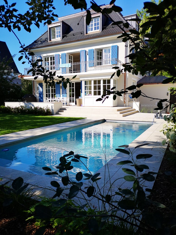 На фото: прямоугольный бассейн среднего размера на заднем дворе в современном стиле с