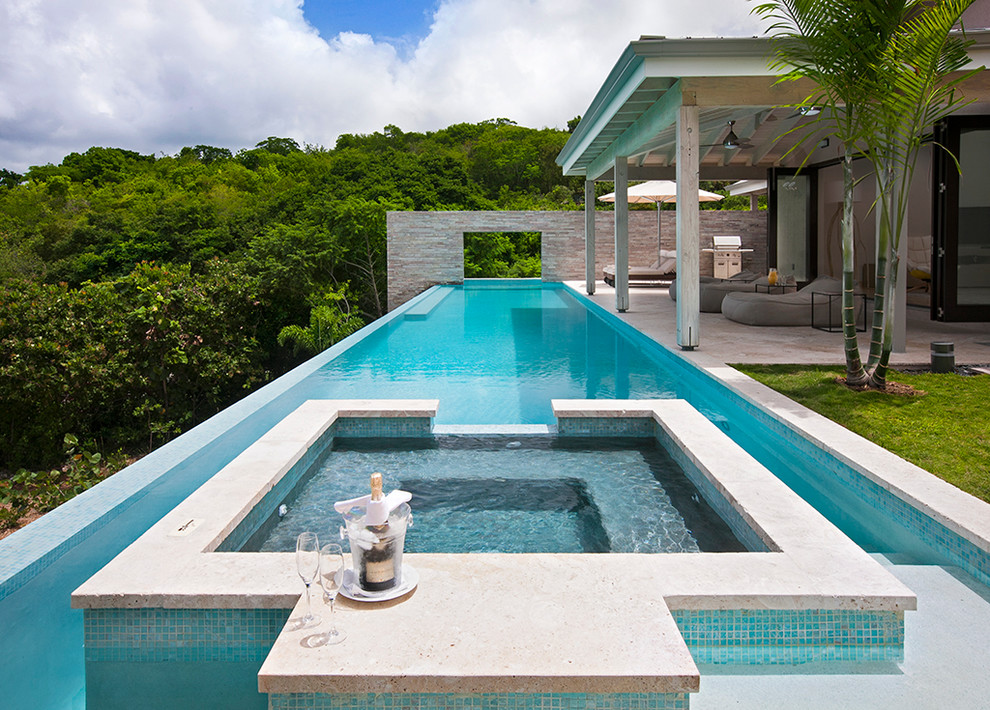 Esempio di una grande piscina a sfioro infinito design rettangolare dietro casa con una vasca idromassaggio