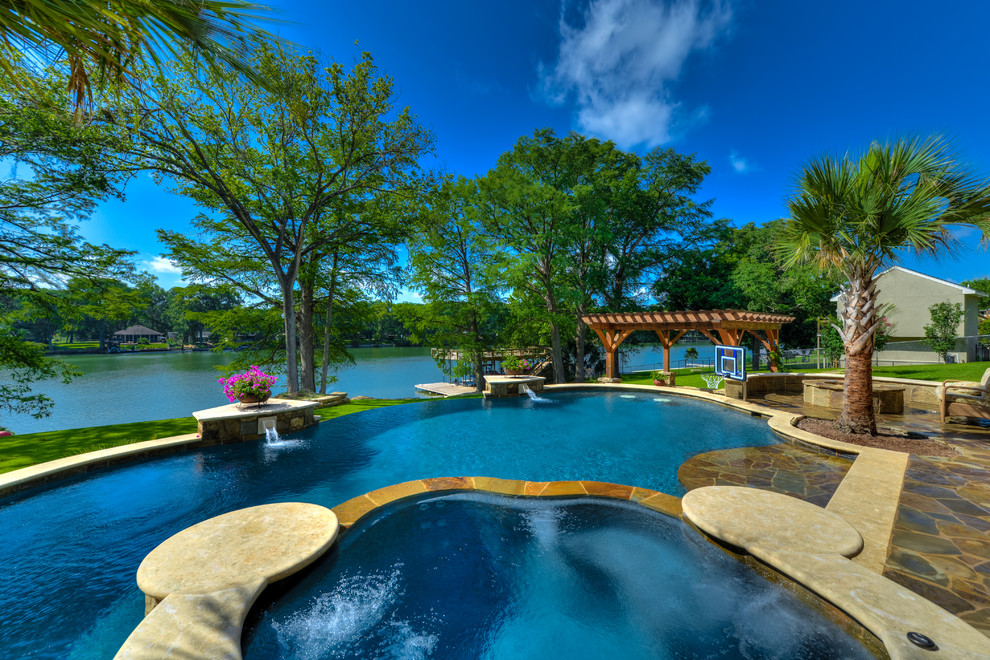 Großer Mediterraner Infinity-Pool hinter dem Haus in individueller Form mit Natursteinplatten in Austin
