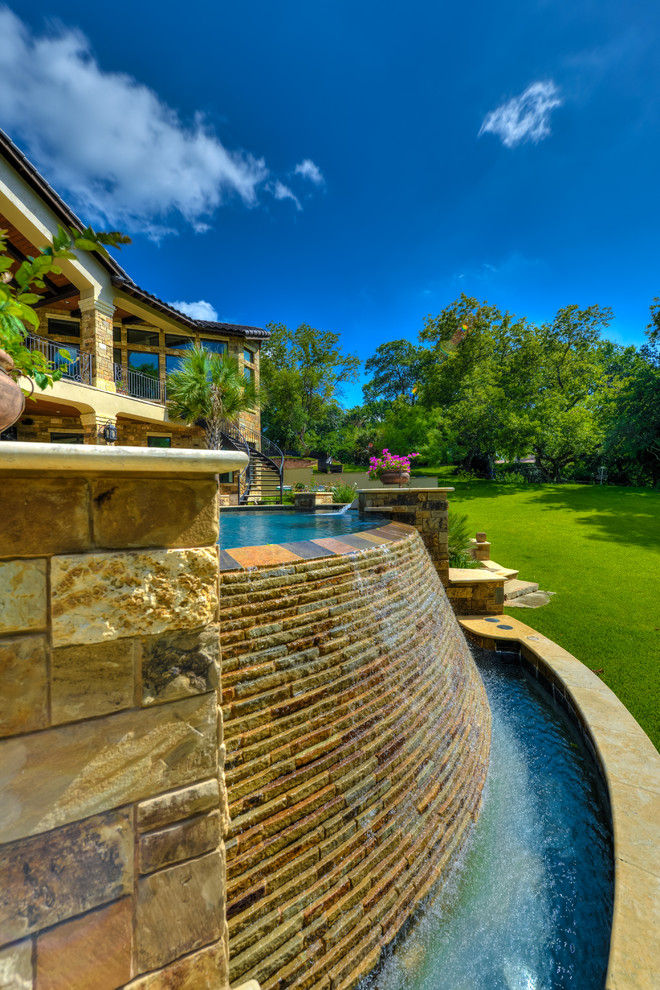 Modelo de piscina con fuente infinita mediterránea grande a medida en patio trasero con adoquines de piedra natural