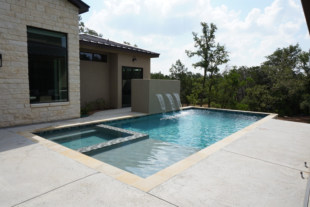 Ispirazione per una grande piscina monocorsia minimal rettangolare dietro casa con fontane e cemento stampato