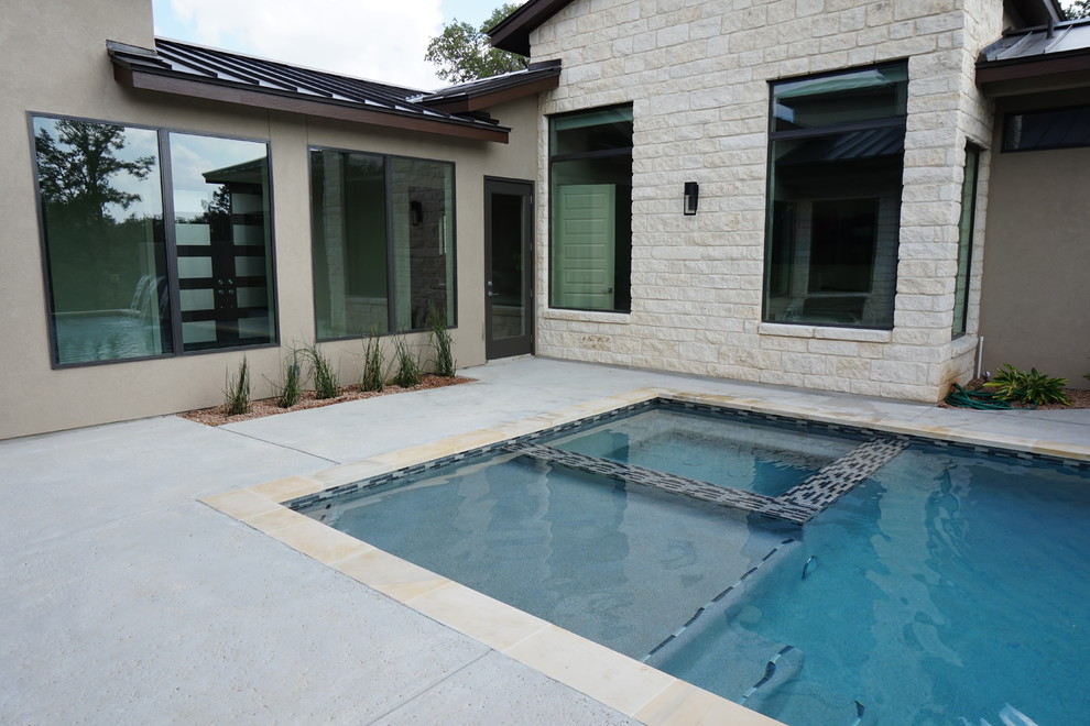 Inspiration for a large contemporary back rectangular lengths swimming pool in Austin with a water feature and stamped concrete.