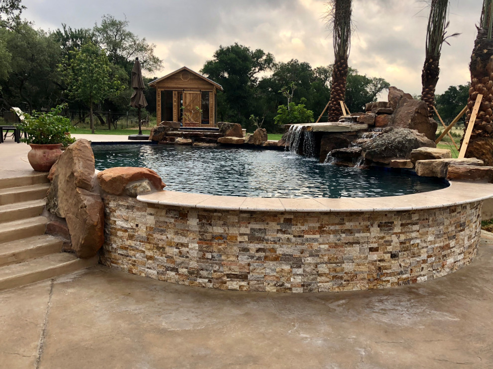 На фото: большой бассейн произвольной формы на заднем дворе в стиле неоклассика (современная классика) с фонтаном и покрытием из бетонных плит