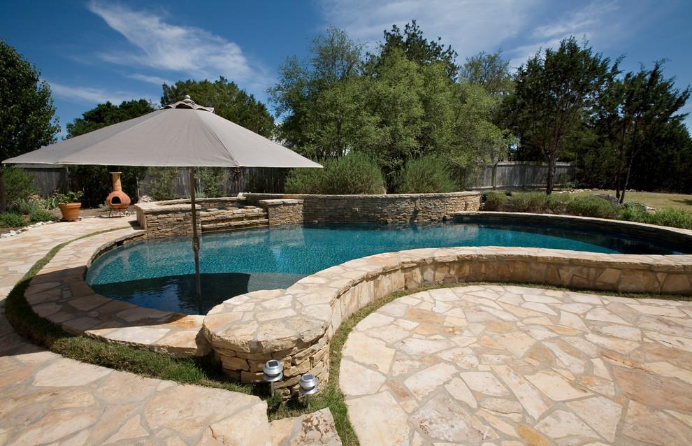 Immagine di una piscina naturale classica personalizzata dietro casa e di medie dimensioni con pavimentazioni in pietra naturale e una vasca idromassaggio