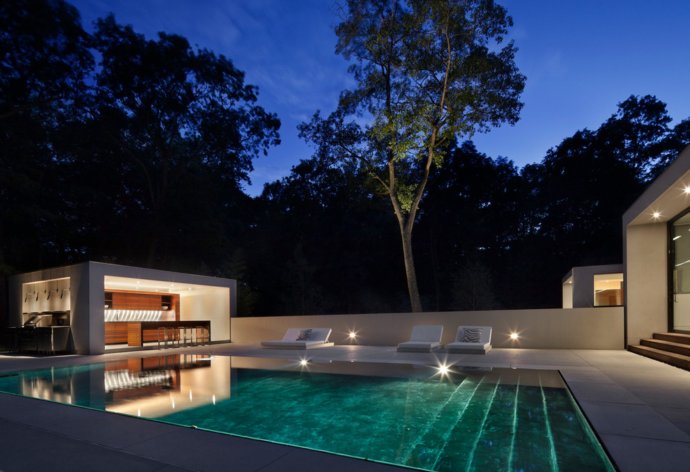 Стильный дизайн: большой прямоугольный бассейн-инфинити на заднем дворе в стиле модернизм с домиком у бассейна и покрытием из бетонных плит - последний тренд