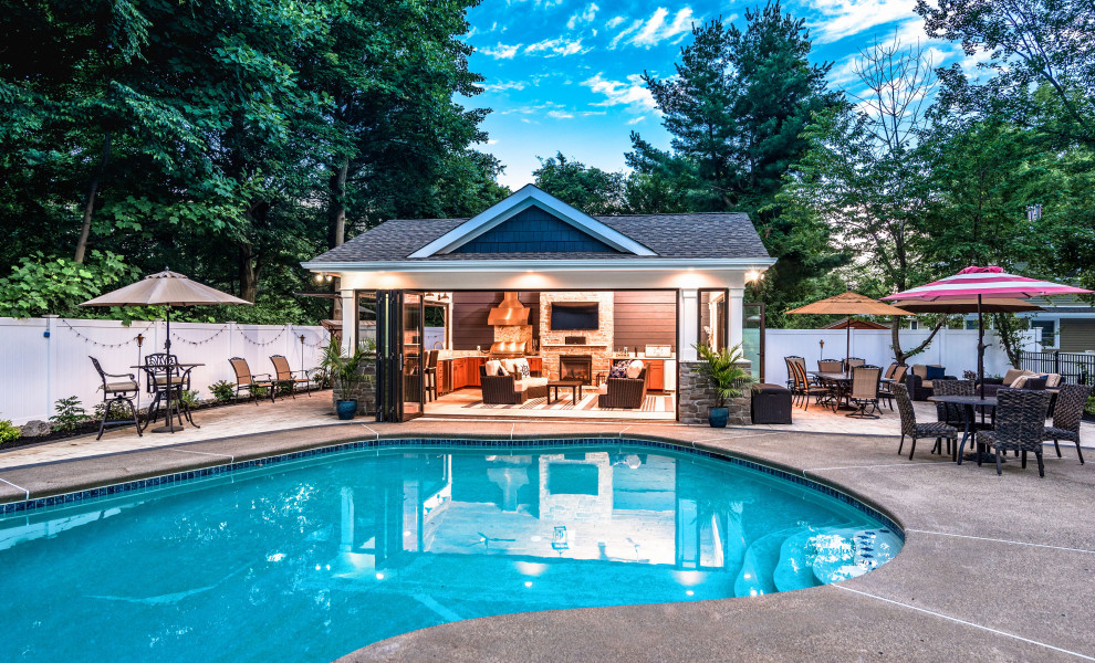 Modelo de casa de la piscina y piscina natural marinera de tamaño medio rectangular en patio trasero con losas de hormigón