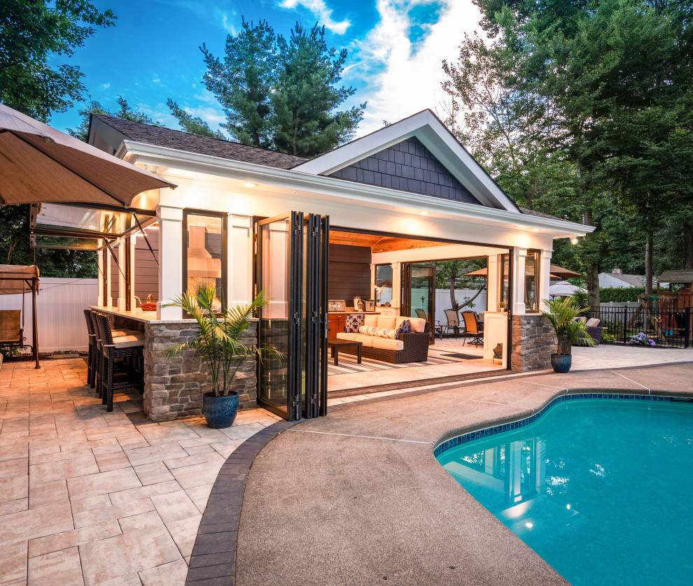 Ejemplo de casa de la piscina y piscina natural marinera de tamaño medio rectangular en patio trasero con losas de hormigón