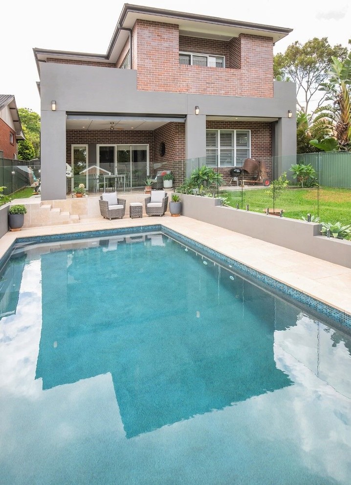 Inspiration for a medium sized contemporary back rectangular swimming pool in Sydney with natural stone paving.