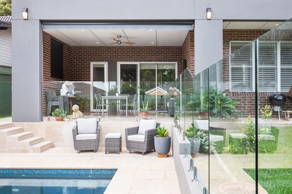 Идея дизайна: прямоугольный бассейн среднего размера на заднем дворе в современном стиле с покрытием из каменной брусчатки
