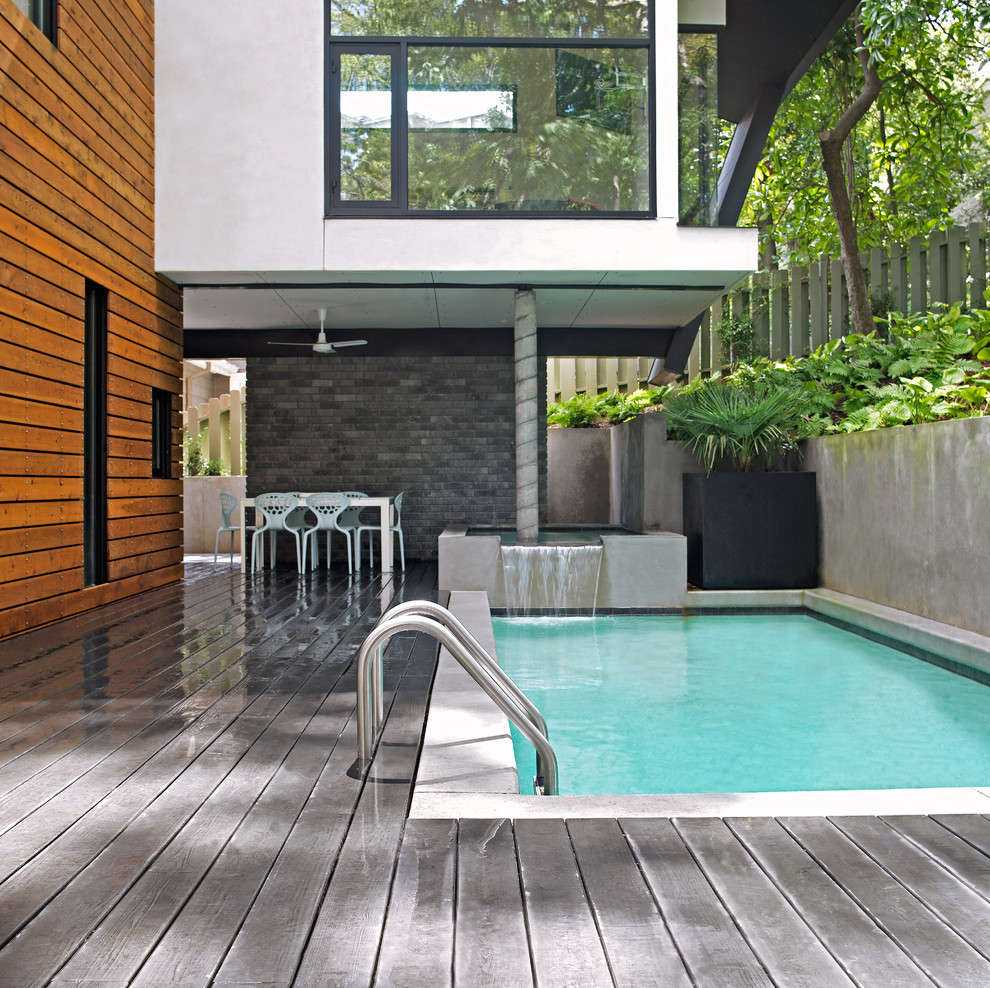 Esempio di una piscina monocorsia design rettangolare di medie dimensioni e dietro casa con pedane