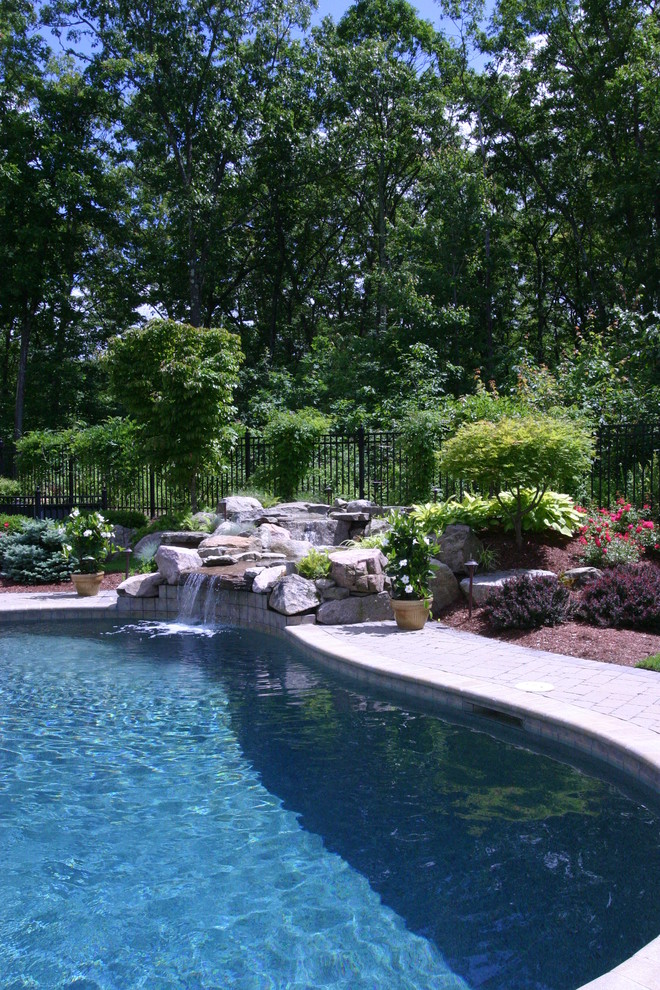 Ejemplo de piscina con fuente clásica renovada extra grande tipo riñón en patio trasero con adoquines de piedra natural