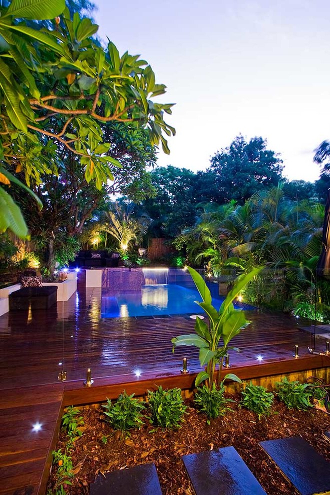 Idee per una piscina fuori terra tropicale personalizzata di medie dimensioni e dietro casa con una vasca idromassaggio e pedane