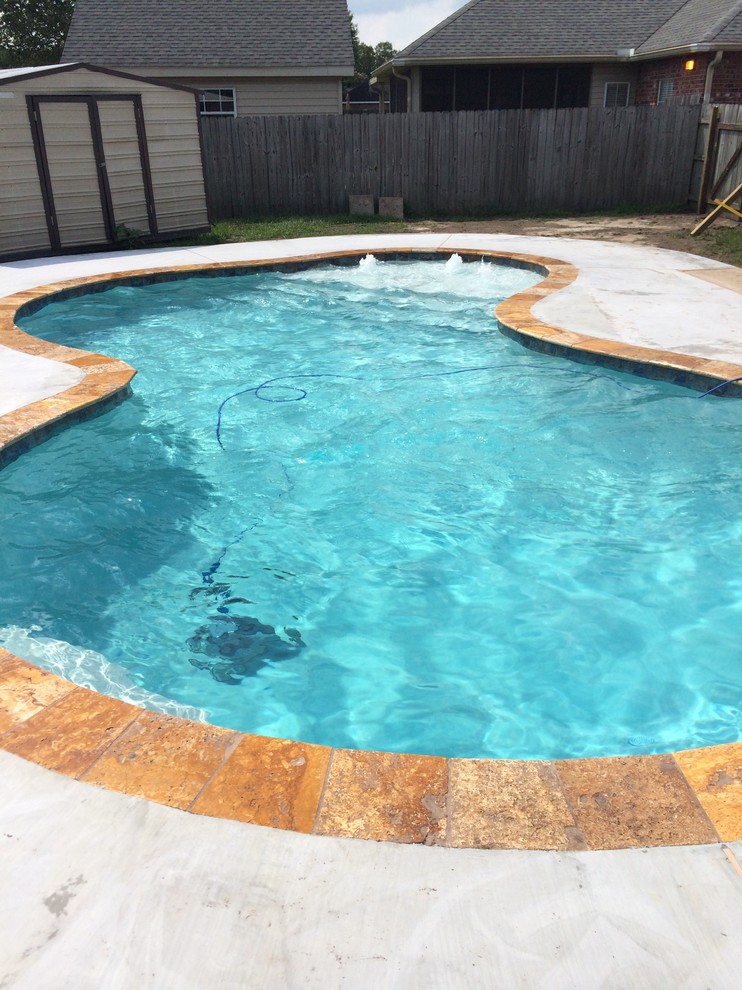 Esempio di una piccola piscina naturale minimalista personalizzata dietro casa con fontane e lastre di cemento
