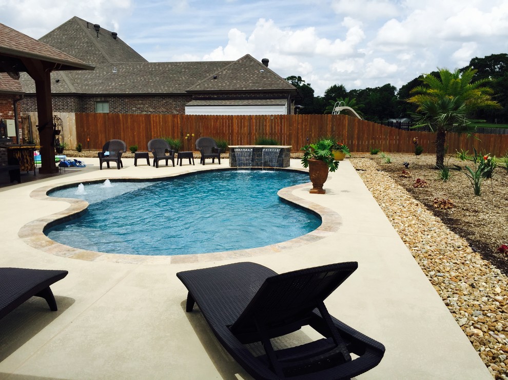 Immagine di una piscina naturale design personalizzata di medie dimensioni e dietro casa con fontane e pedane
