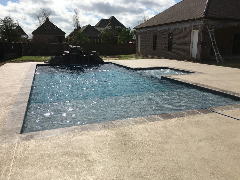 Ispirazione per una grande piscina naturale minimal rettangolare dietro casa con fontane e pedane