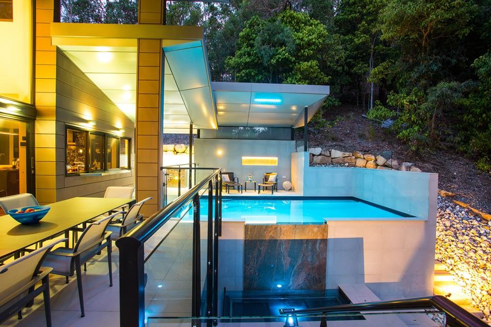 Immagine di una grande piscina a sfioro infinito moderna rettangolare nel cortile laterale con una dépendance a bordo piscina e pavimentazioni in pietra naturale