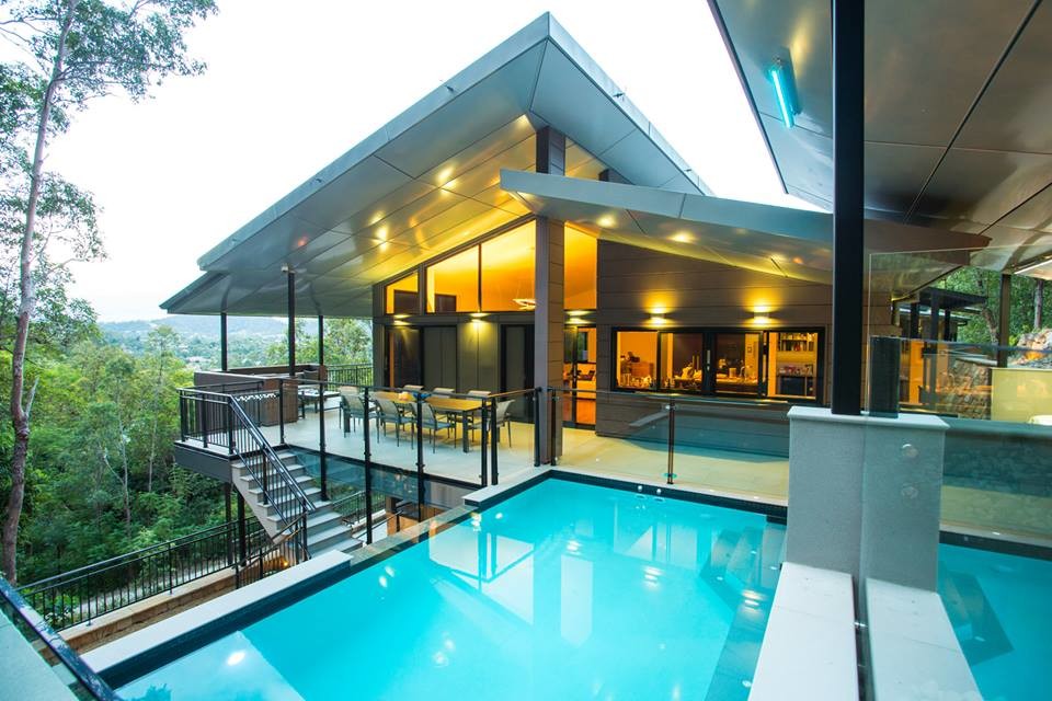 Diseño de casa de la piscina y piscina infinita moderna grande rectangular en patio lateral con adoquines de piedra natural