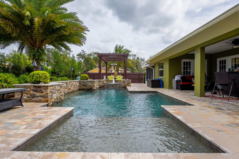 Bild på en stor funkis anpassad pool på baksidan av huset, med en fontän och naturstensplattor