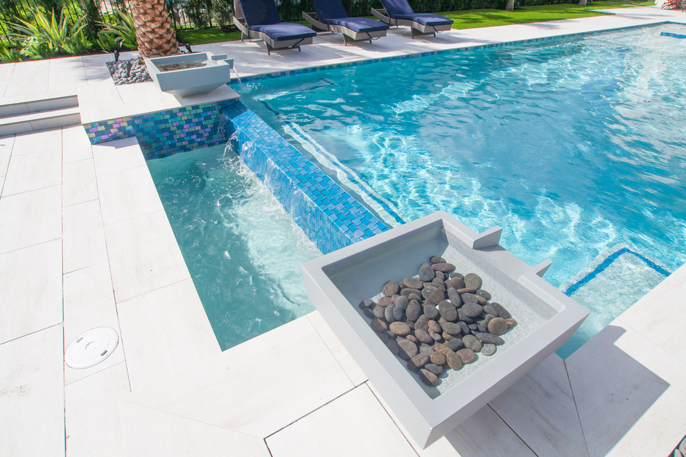 Foto di una grande piscina a sfioro infinito minimalista rettangolare dietro casa con una vasca idromassaggio