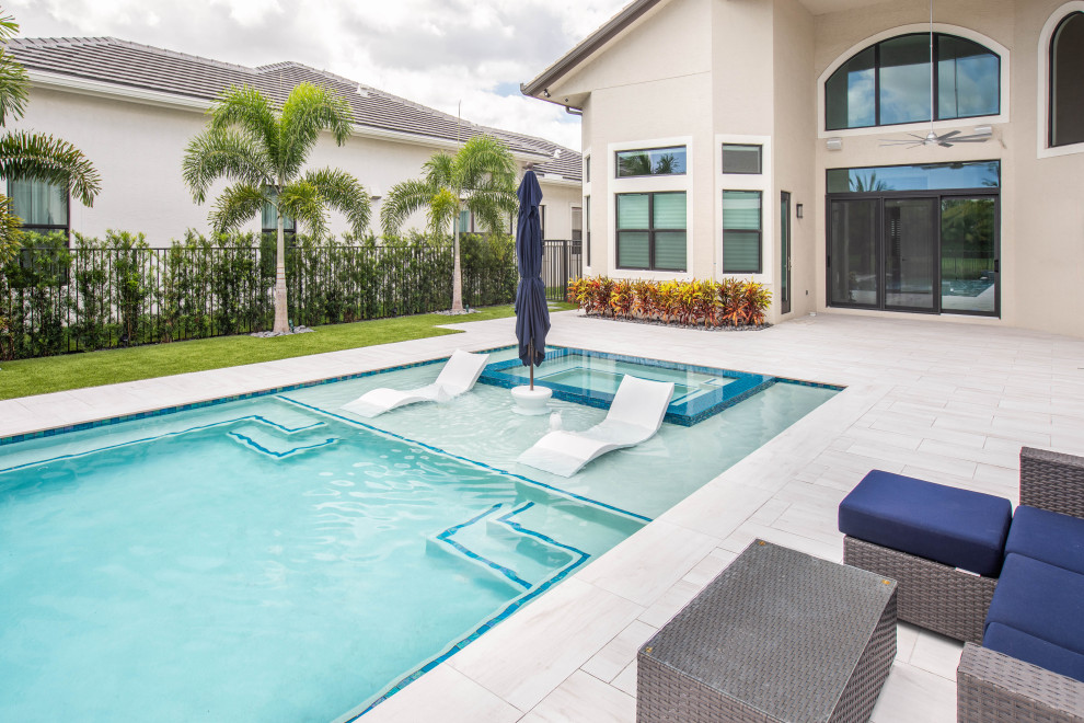 Hot tub - large modern backyard rectangular infinity hot tub idea in Miami