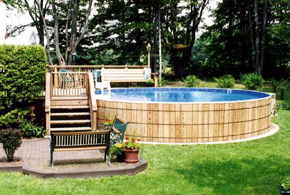 Immagine di una piscina fuori terra tradizionale rotonda dietro casa con lastre di cemento