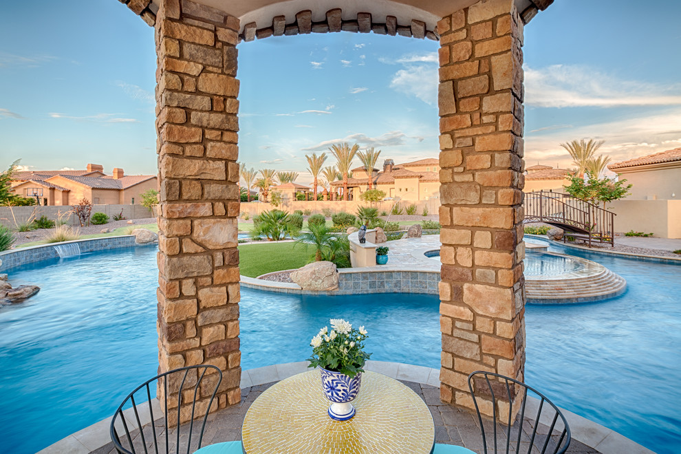 Example of a large tuscan backyard concrete paver and custom-shaped natural pool design in Phoenix