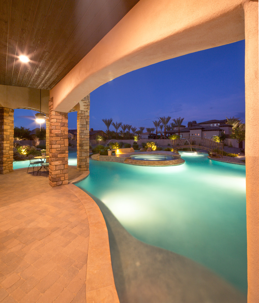 Imagen de piscina natural mediterránea grande a medida en patio trasero con adoquines de hormigón