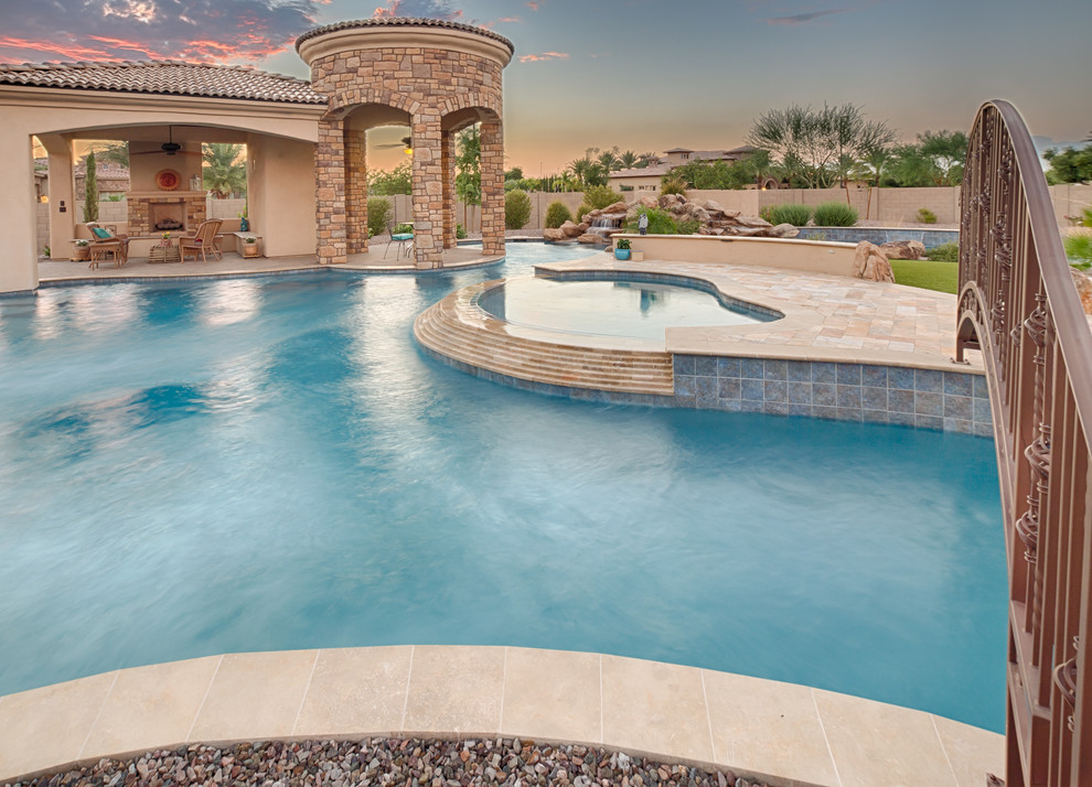 Photo of a large mediterranean back custom shaped natural swimming pool in Phoenix with concrete paving.