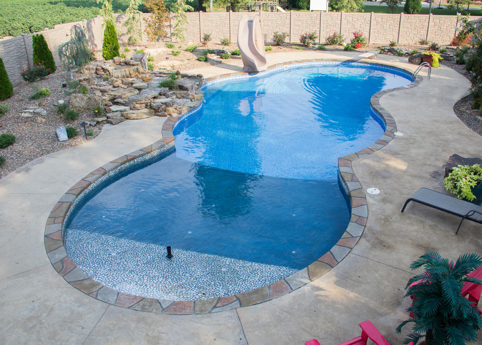 Inspiration for a large tropical backyard stamped concrete and custom-shaped pool fountain remodel in Chicago