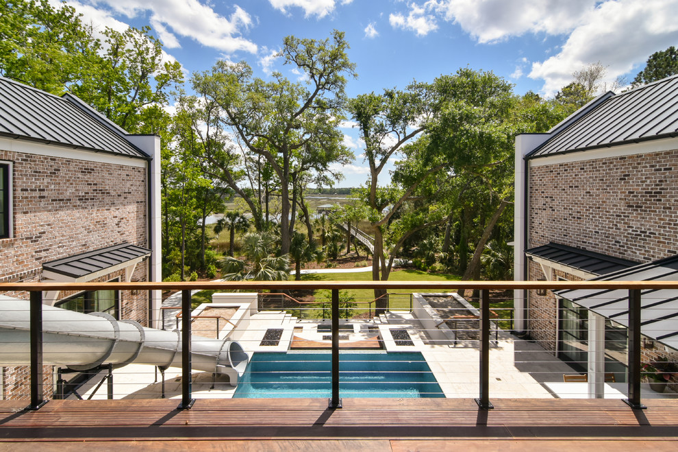 Ejemplo de piscina con tobogán infinita tradicional renovada grande a medida en patio con adoquines de piedra natural