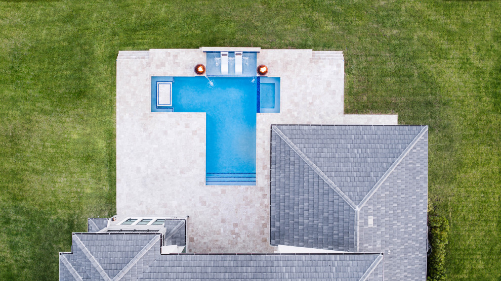 Großer Moderner Pool hinter dem Haus in individueller Form mit Wasserspiel und Natursteinplatten in Miami