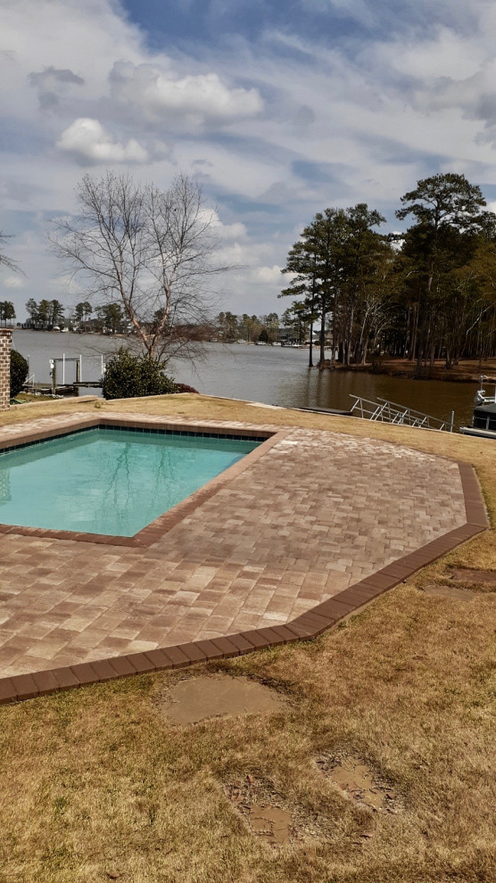Foto de piscina natural tradicional de tamaño medio rectangular en patio trasero con adoquines de hormigón