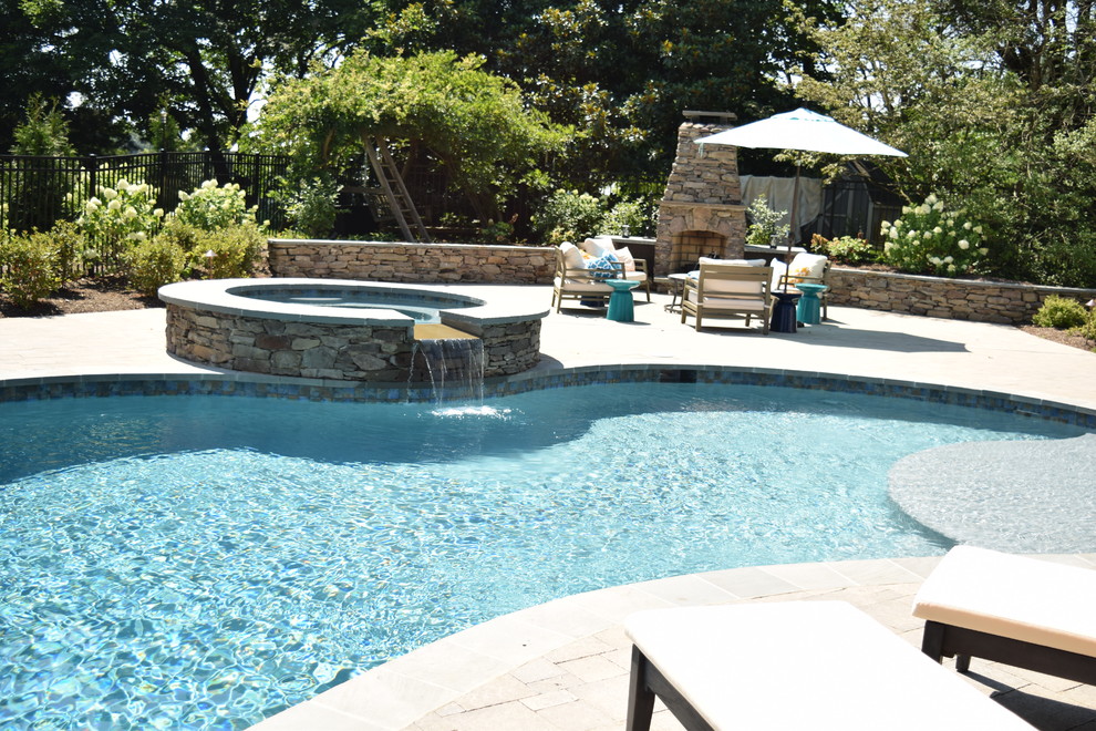 Diseño de piscinas y jacuzzis naturales tradicionales grandes tipo riñón en patio trasero con suelo de hormigón estampado