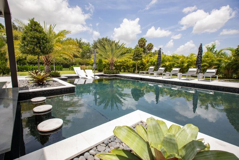 Идея дизайна: огромный естественный, прямоугольный бассейн на заднем дворе в стиле модернизм с домиком у бассейна и покрытием из каменной брусчатки