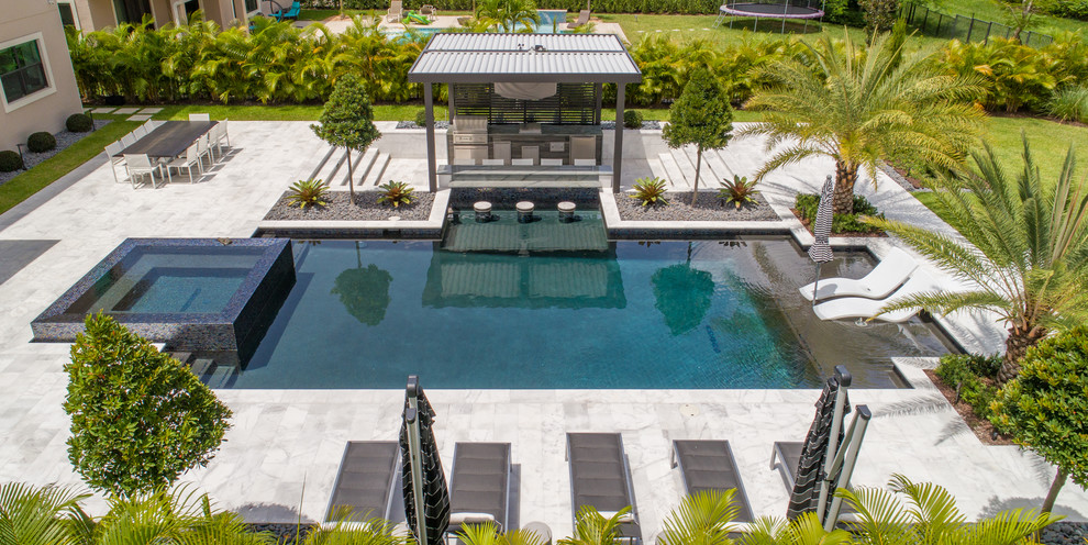 Immagine di un'ampia piscina naturale minimalista rettangolare dietro casa con una dépendance a bordo piscina e pavimentazioni in pietra naturale
