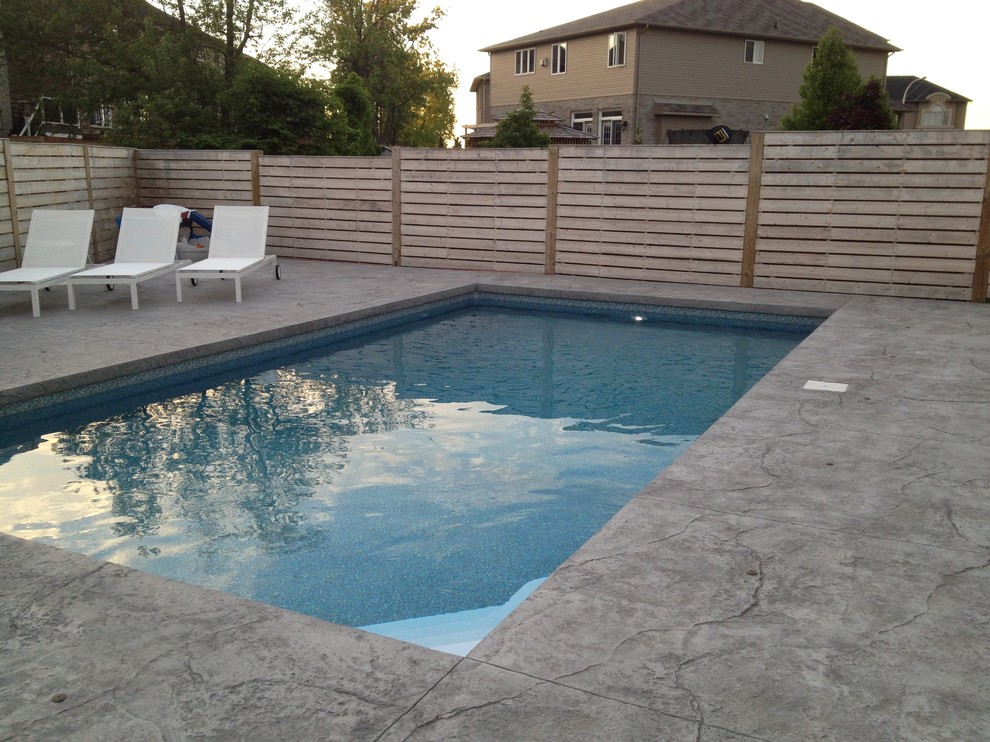 This is an example of a medium sized modern back rectangular lengths swimming pool in Toronto with concrete slabs.