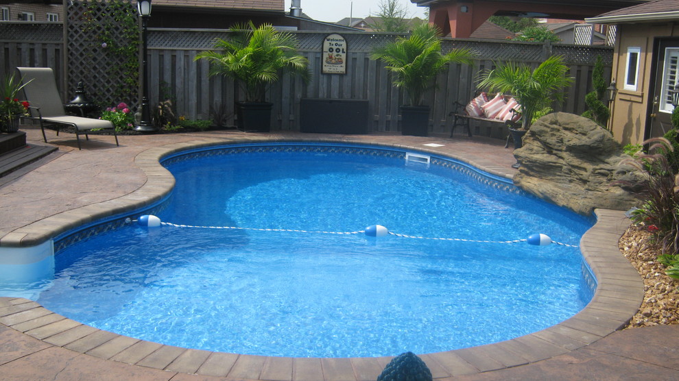 Immagine di una piscina monocorsia tropicale a "C" di medie dimensioni e dietro casa con pavimentazioni in mattoni