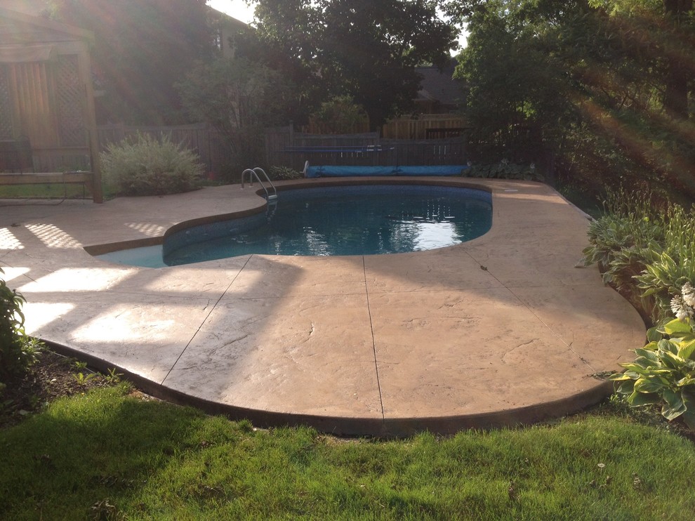 Idee per una piscina monocorsia classica a "C" di medie dimensioni e dietro casa con lastre di cemento