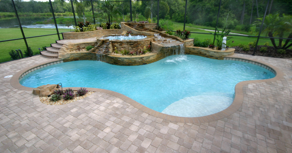 Ispirazione per una piscina naturale tradizionale personalizzata di medie dimensioni e dietro casa con una vasca idromassaggio e pavimentazioni in pietra naturale