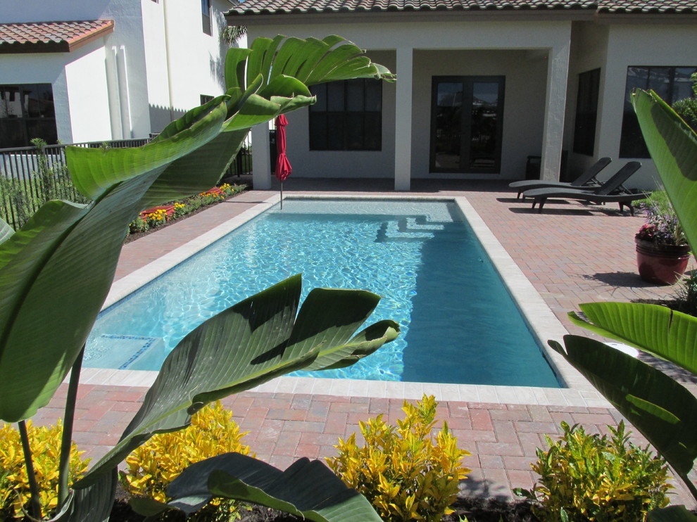 Imagen de piscina moderna de tamaño medio rectangular en patio trasero con adoquines de ladrillo