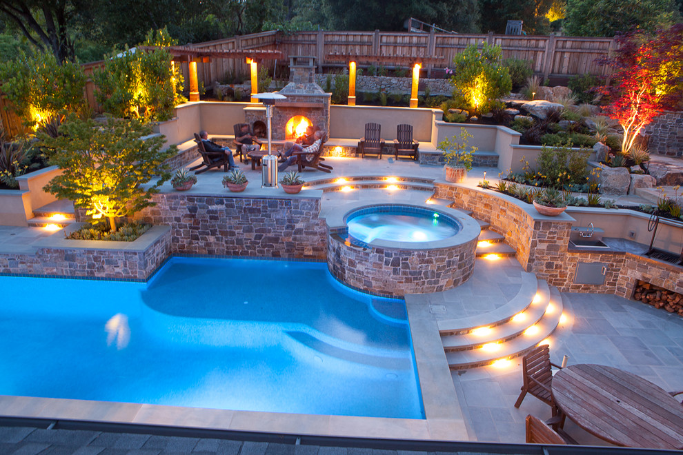 Esempio di una grande piscina chic a "L" dietro casa con una vasca idromassaggio e pavimentazioni in pietra naturale