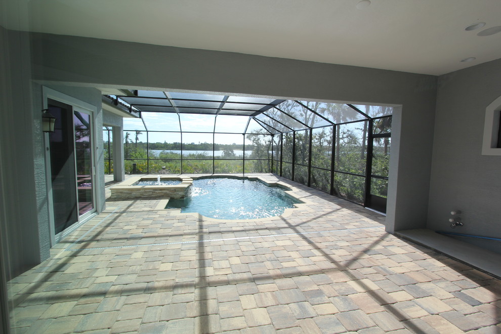 На фото: большой спортивный бассейн произвольной формы в доме в средиземноморском стиле с джакузи и мощением тротуарной плиткой