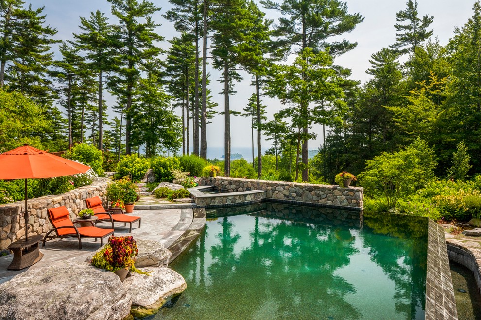 Ejemplo de piscina natural de estilo americano de tamaño medio a medida en patio trasero con adoquines de piedra natural